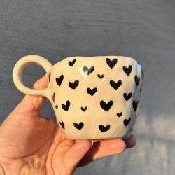 Handgemachte bauchige Keramiktasse mit schwarzen Herzen